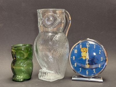 un hibou en verre et une horloge posés l'un à côté de l'autre