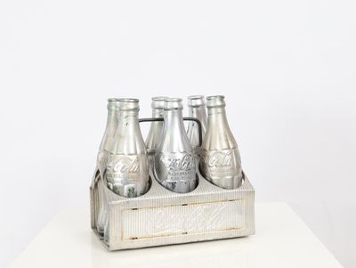 four bottles of soda in a wooden crate on a table