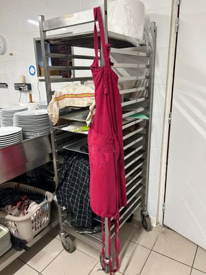a red apron hanging on a rack in a kitchen