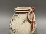 a white vase with a red ribbon on the handle