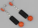une paire de boucles d'oreilles noires et orange ornées de perles sculptées