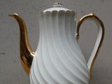 une cafetière blanche et dorée posée sur une table
