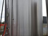 un homme qui se tient à côté d'un grand réservoir