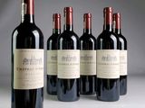 four bottles of red wine are lined up on a table