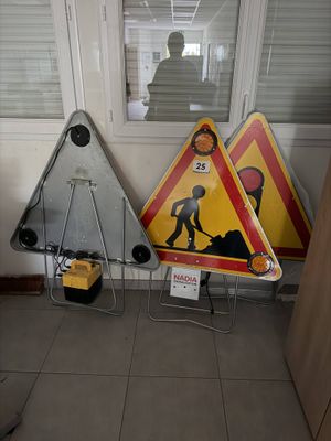 trois panneaux de signalisation posés par terre près d'une fenêtre