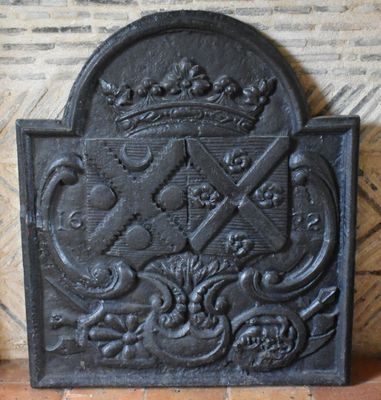 un vieil écran de cheminée en fonte surmonté d'une couronne