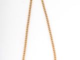 a gold beaded necklace on a white background