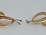 two gold tone earrings with twisted leaves on them