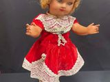 a close up of a doll in a red dress on a white pedestal