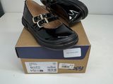 une paire de chaussures en cuir noir avec des boucles, posée sur une boîte en carton