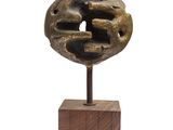 statue représentant un visage, posée sur un socle en bois, sur fond blanc