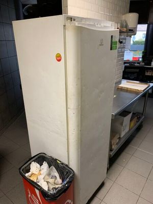 un réfrigérateur blanc dans une cuisine, avec une poubelle devant