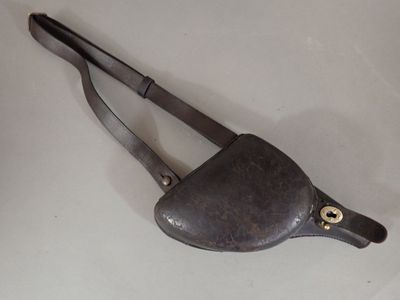 un sac à main en cuir muni d'une poignée métallique, posé sur une surface blanche