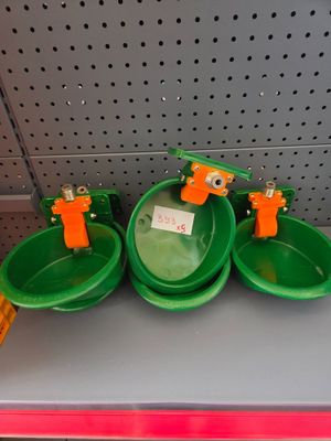 three green bowls with orange handles on a shelf