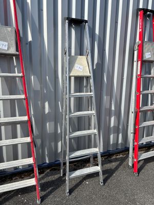 Plusieurs échelles sont alignées contre un mur devant un immeuble.