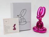 pink balloon rabbit sculpture next to a business card and a card holder