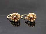 paire de boucles d'oreilles en or ornées de grenats sur fond noir