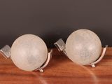 pair of white glass globes on metal bases on a wooden table