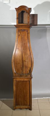 une grande horloge de parquet en bois, placée dans un coin de la pièce