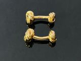 a pair of gold plated nose rings on a black surface