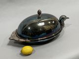 a silver plate with a lid and a lemon next to it