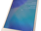 a white tablet with a blue screen sitting on a stand