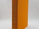 an orange book sitting on top of a white table next to a white wall