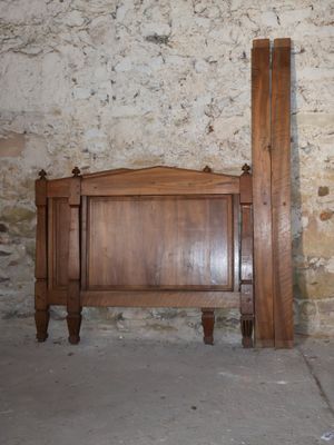 a bed with a wooden headboard next to a brick wall
