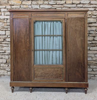 an old wooden cabinet with a glass door and a brick wall in the background