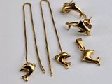 trois colliers en or et une paire de boucles d'oreilles posés sur une surface blanche