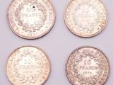 four different coins are shown in a row on a white surface