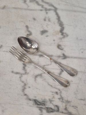 une cuillère et une fourchette en argent posées sur une table en marbre