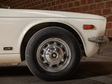 a white car parked in front of a brick wall