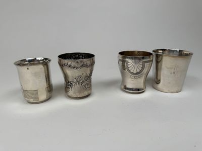 trois verres à shot en argent et un verre à shot en argent posés sur une surface blanche