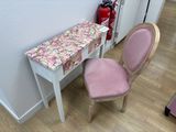 a pink chair next to a white table with a pink cover