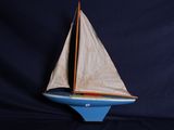un petit voilier qui flotte sur une étendue bleue