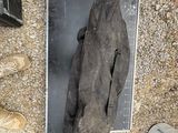 une photo d'un morceau de métal posé par terre à côté d'une paire de chaussures