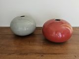 deux vases posés sur une table en bois, avec un mur blanc en arrière-plan