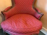 une vieille chaise avec une assise rembourrée rouge dans une pièce