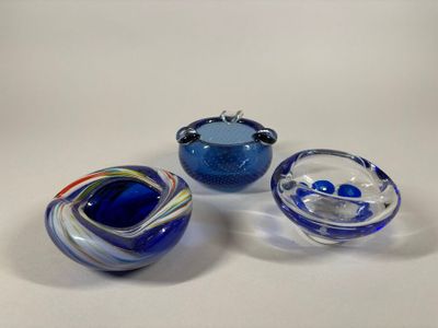 three blue glass bowls with swirl designs on them sitting on a white surface