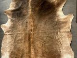 a brown and white cow skin rug on the wall