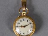 une petite montre de poche en or avec un cadran blanc