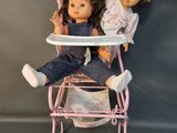 two dolls that are sitting in a high chair