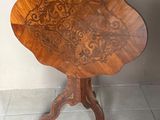 une petite table en bois au plateau sculpté, posée sur un sol carrelé