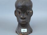 une image représentant la tête d'un homme sculptée, sur laquelle est accrochée une étiquette