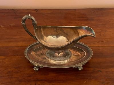a silver gravy sitting on top of a wooden table