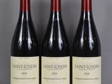 trois bouteilles de vin de Saint-Joseph sont posées sur une table en verre