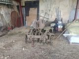 un tracteur et une charrue dans la cour d'un vieux bâtiment