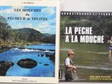 two books on a table with a man fly fishing in the river