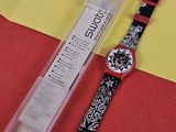 une montre noire et blanche posée à côté d'un bout de papier rouge et jaune